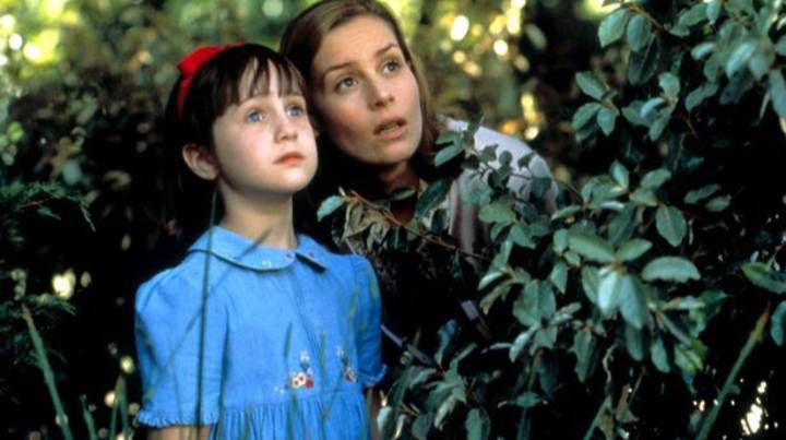 Still from the film MATILDA, with a mother and child peering up from the bushes.