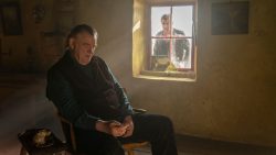 Still of The Banshees of Inisherin in which Colin Farrell looks through a window at Brendan Gleeson