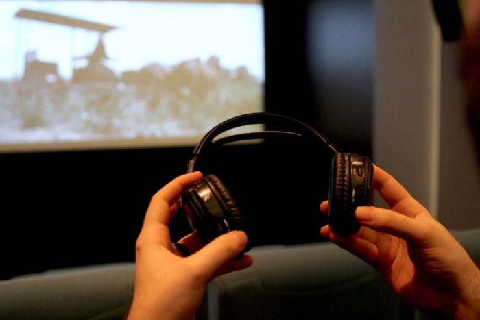headphone receiver being held in hands in theater in front of movie screen